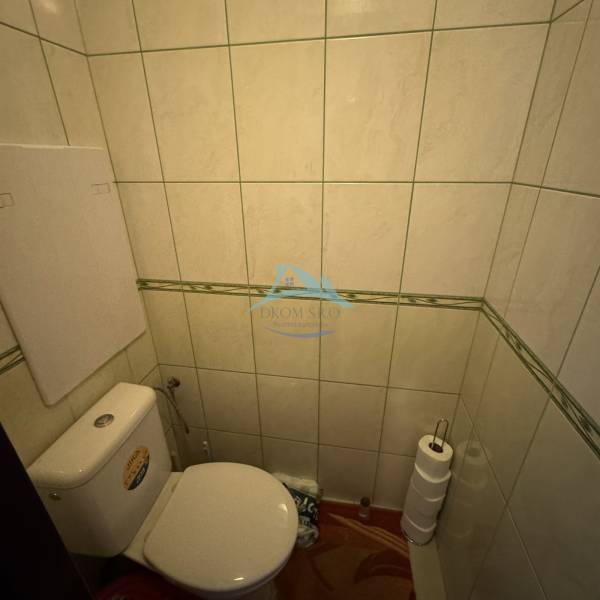 A toilet with tiles, toilet paper in a 4-room apartment.