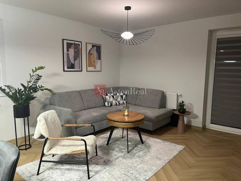 Living room with a sofa, table, plant, and wooden decor flooring in a 3-room apartment.