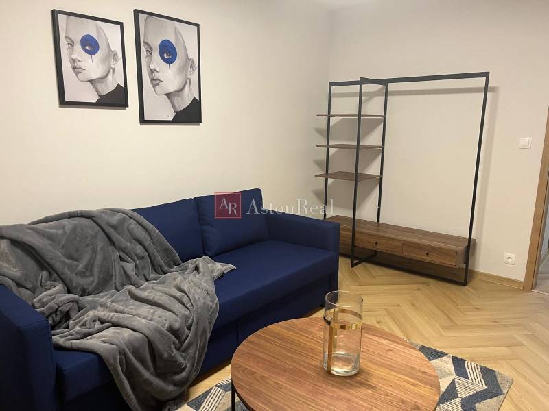 Living room with a blue sofa, modern paintings, and a shelving system in a three-room apartment.