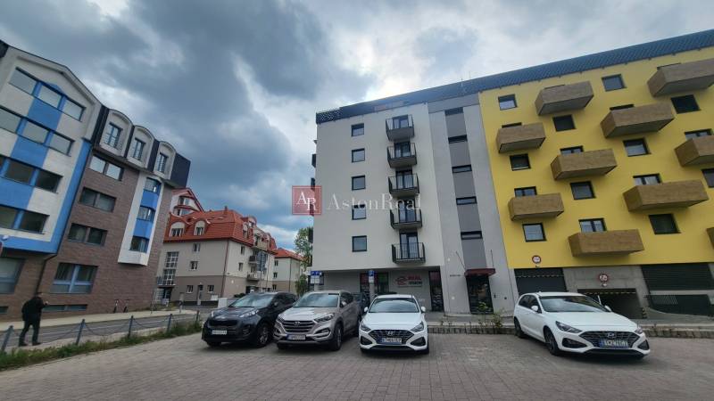 Apartment buildings on Hviezdoslavova Street in Poprad with a parking lot and an overcast sky.