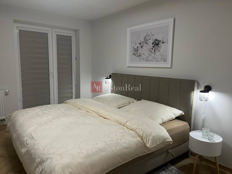 A bedroom in a 3-room apartment with a light bed and subtle wall decor.