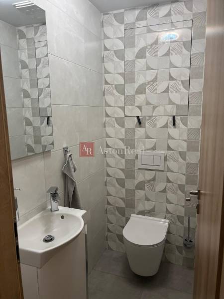 A bathroom in a 3-room apartment with geometric light gray tiles, a sink, and a toilet.