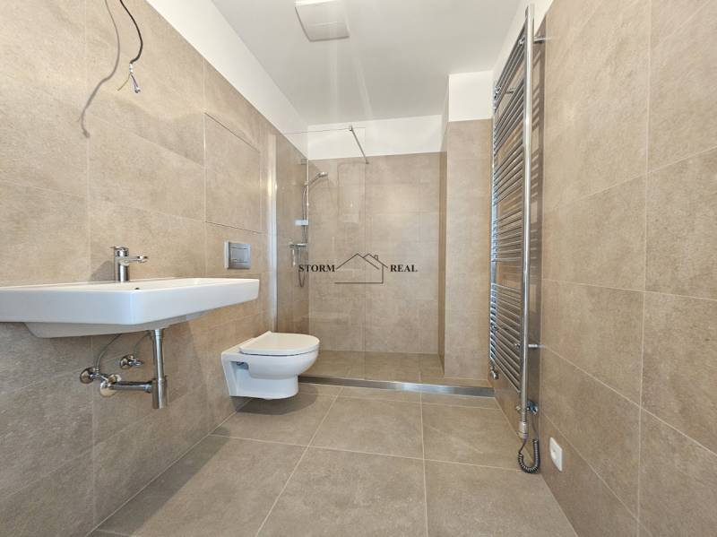 Bathroom with ceramic tiles, wall-hung toilet, and shower in a studio apartment.
