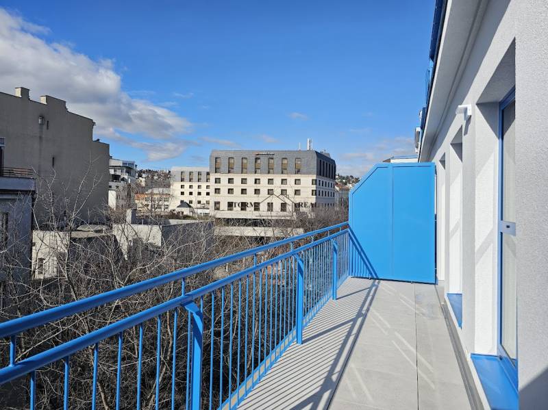 A balcony with blue railings offers a view of buildings in Bratislava - Old Town.