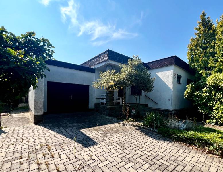 A family house in Ivanka pri Dunaji with a garage and a flower bed, on a paved walkway.