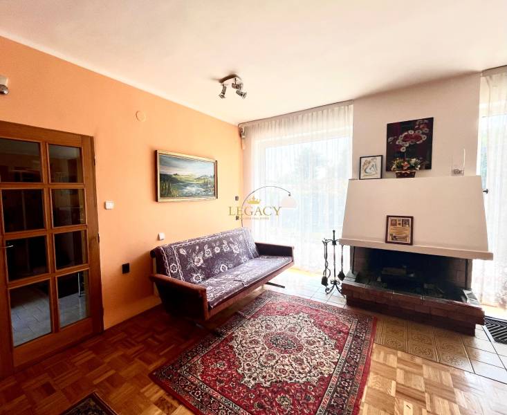 Living room in a family house with a fireplace, sofa, and wooden decor flooring.