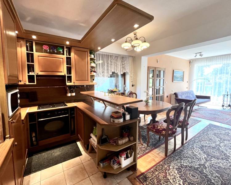 Interior of a family house with a kitchen unit, dining table, and floor with a wooden decor.