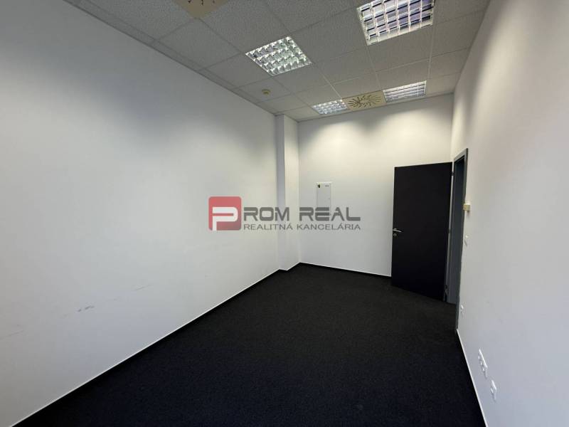 Offices with white walls and dark carpet.