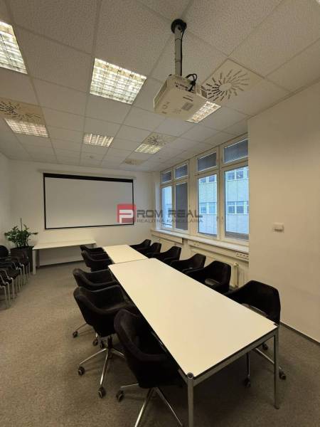 Conference room in offices with a projector, tables, and chairs, ready for meetings.