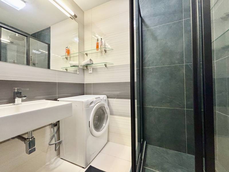 Bathroom of a 2-room apartment with a washing machine, shower, and mirror.
