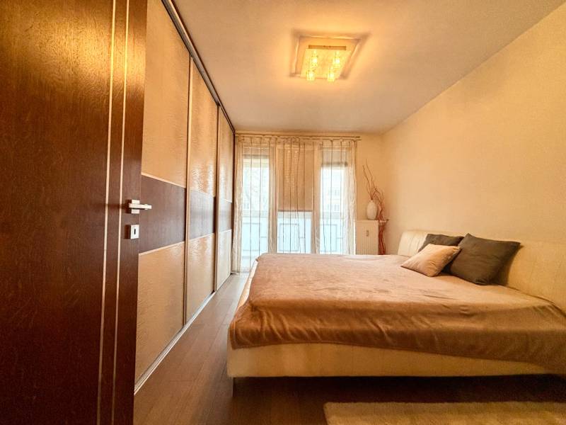 Bedroom in a 2-room apartment with a large bed and a floor with a wooden decor.