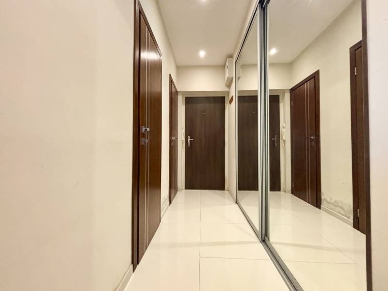 A hallway with a white floor and a mirrored wardrobe in a 2-room apartment.