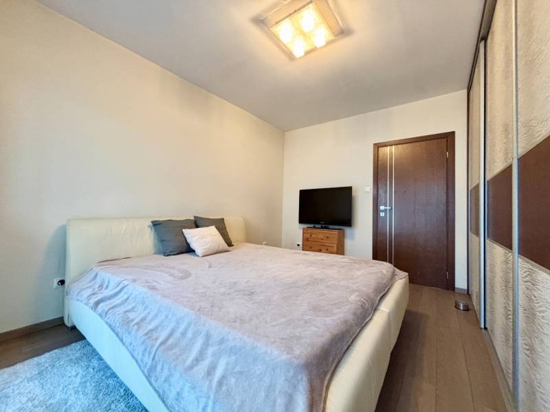 A bedroom in a 2-room apartment with a comfortable bed, a television, and a wooden decor floor.