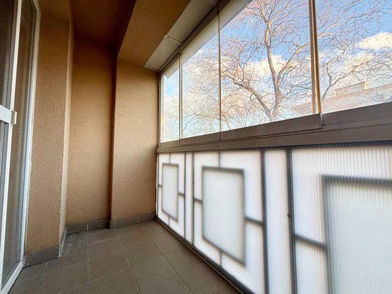 A glazed balcony with a view of trees, part of a 2-room apartment.