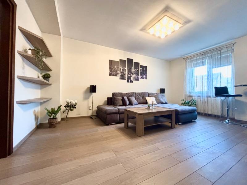 Living room in a two-room apartment with a wooden decor floor and a comfortable sofa.
