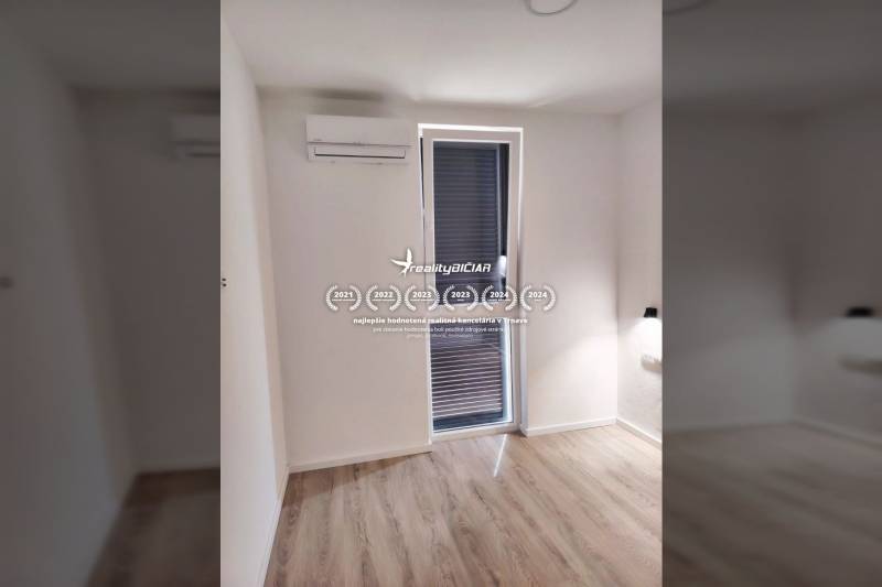 A room in a family house with a window, air conditioning, and a wooden decor floor.