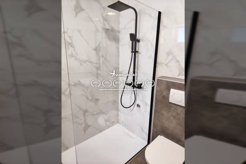 A shower enclosure and toilet in a family house with marble tiles.