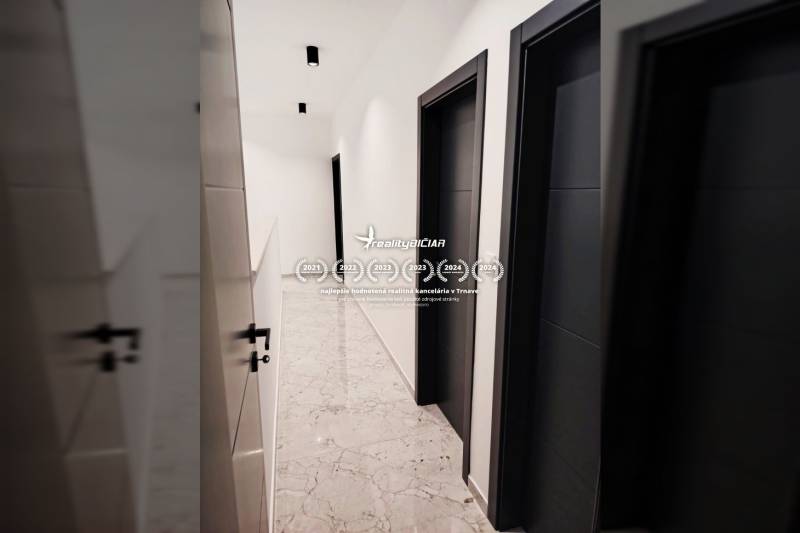 A hallway in a family house with tiles and dark doors.
