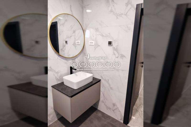 A bathroom in a family house with a sink on a cabinet, a mirror, and tiles with a marble pattern.