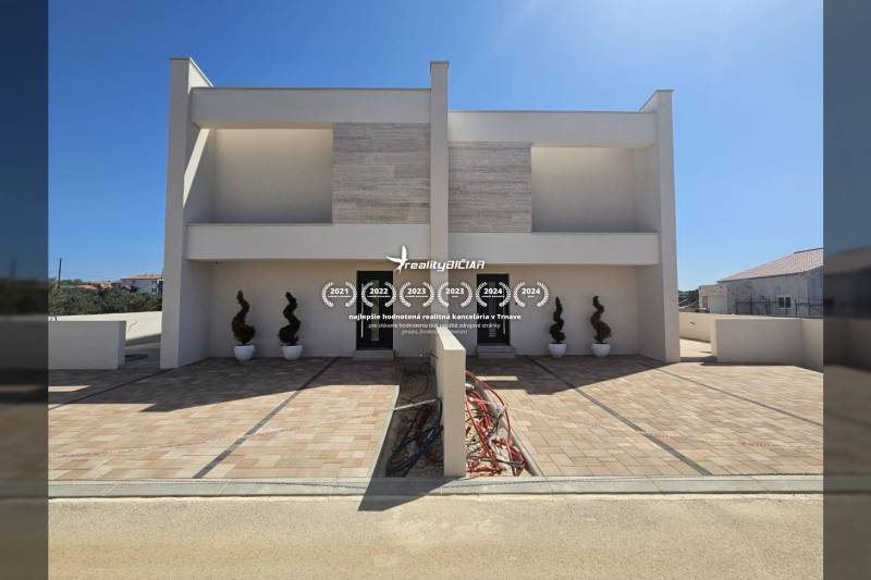 A family house on Mulo Street in Vrsi with a paved walkway and decorative plants.