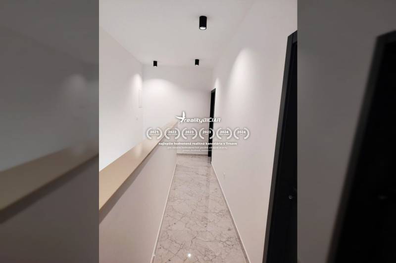 A narrow hallway in a family house with glossy tiles and white walls.
