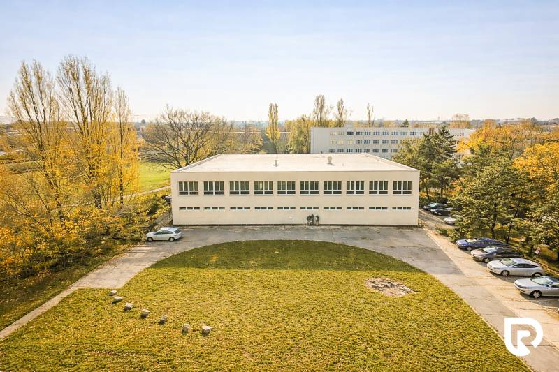 A building surrounded by greenery and a parking lot in Bratislava - Ružinov on Šándorova Street.