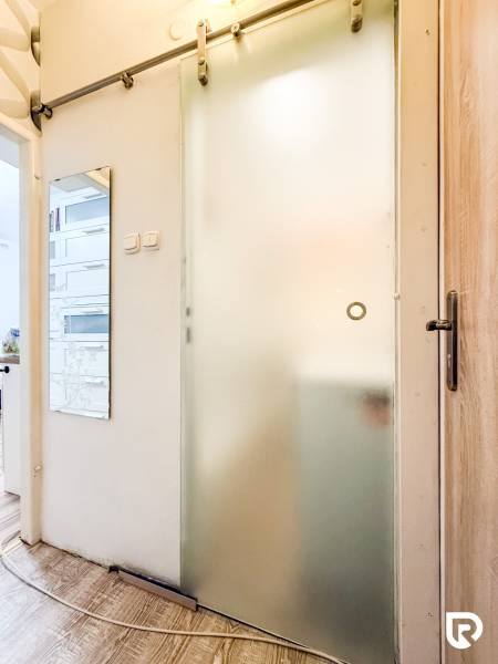 Sliding glass doors in a studio apartment with wood-patterned flooring and a wall mirror.