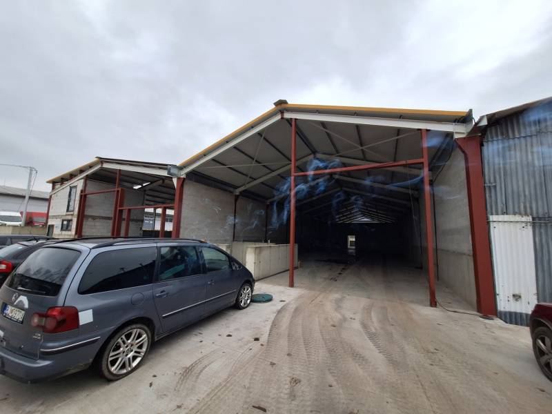 Warehouses and halls on Strojnícka Street in Prešov, a parking lot with vehicles in front of the entrance.