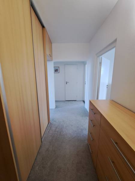 A hallway in a 3-room apartment with a built-in wardrobe and a chest of drawers with a wooden decor.