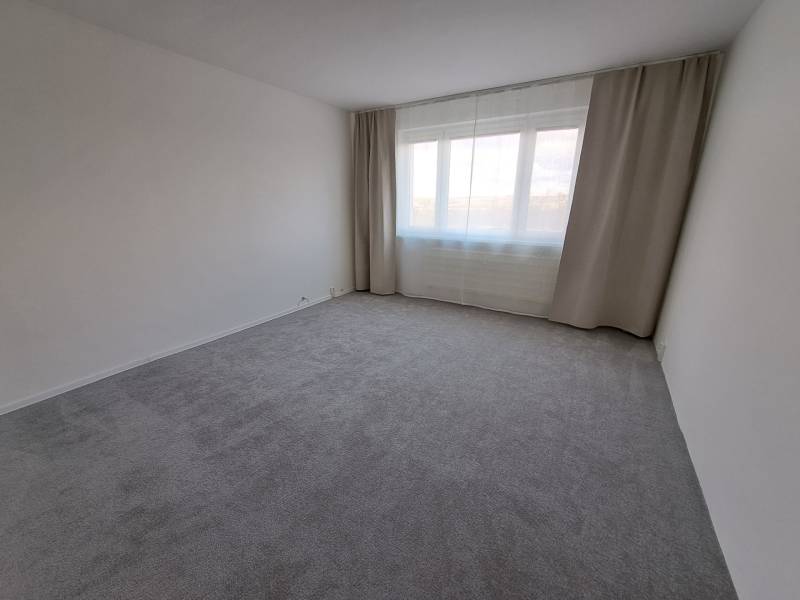 A spacious room in a 3-room apartment, with large windows and curtains.