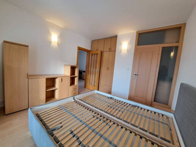 A bedroom in a 4-room apartment with wooden decor furniture and a bed without a mattress.