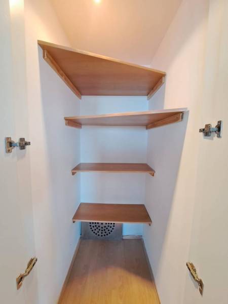 A wardrobe with built-in shelves in a 4-room apartment with a wood-patterned floor.