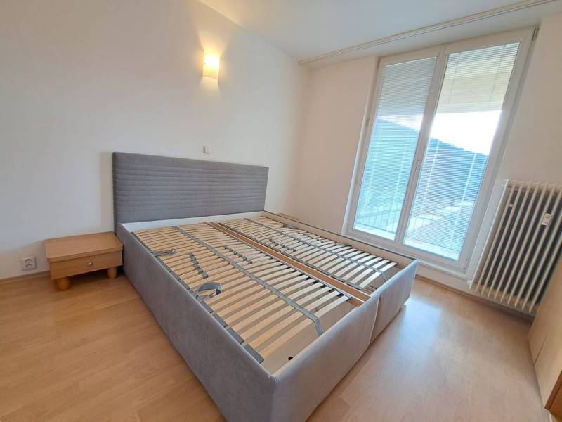 Bedroom in a 4-room apartment with a bed and a nightstand, floor with wood decor.