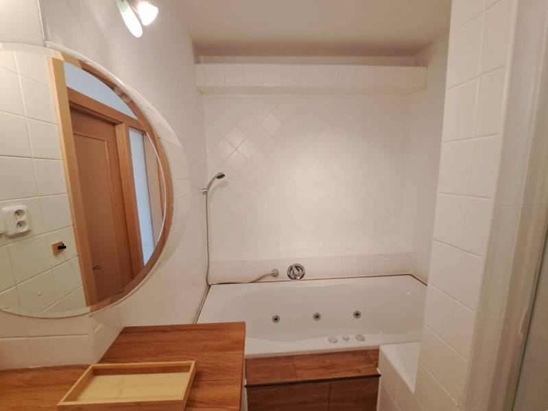 A bathroom with a mirror and a bathtub in a 4-room apartment; use of wooden decor.