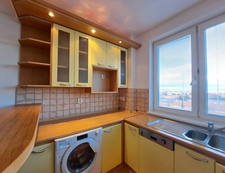 A kitchen in a 4-room apartment with a wooden decor, a sink, and a view from the window.