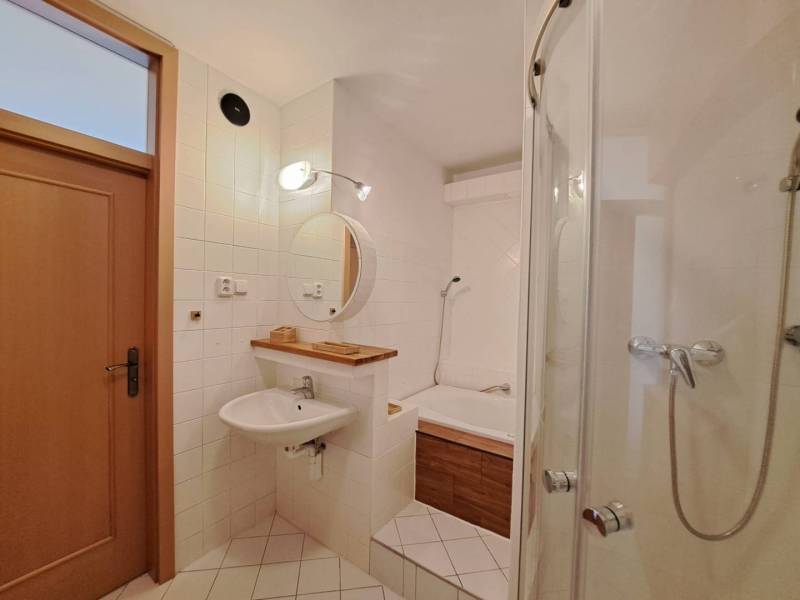 A bathroom in a 4-room apartment with a bathtub, a shower, and white tiles.