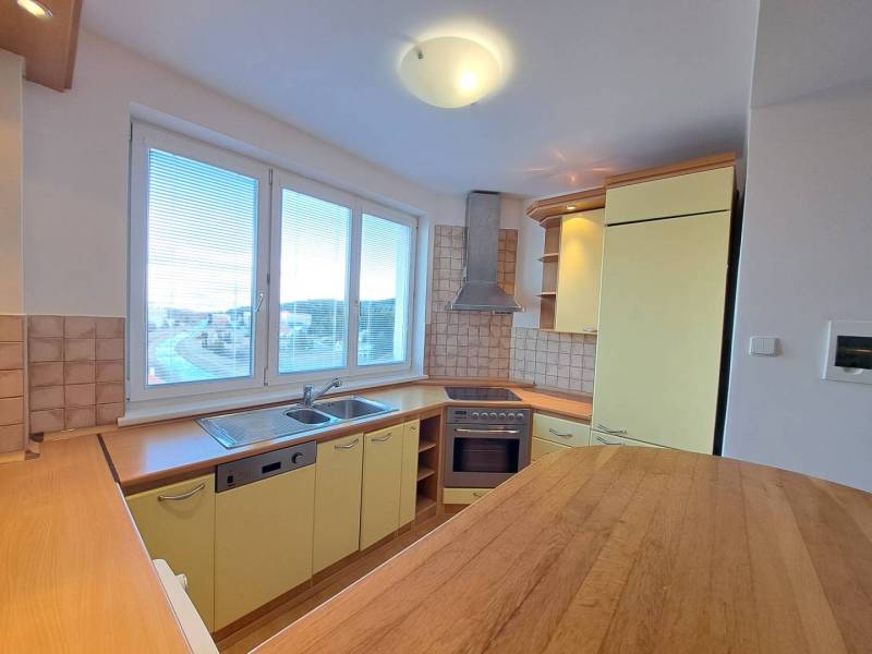 A kitchen in a 4-room apartment with a wooden decor floor and yellow cabinets.