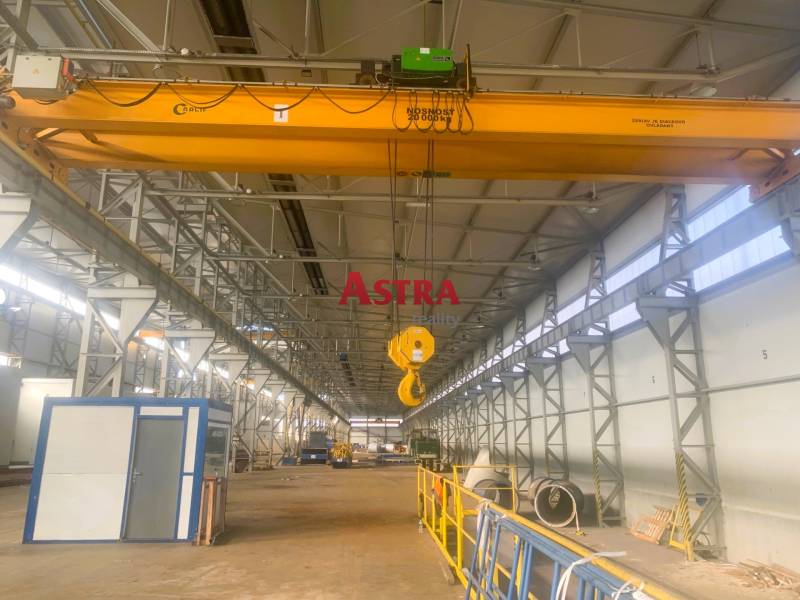 Production facilities with industrial cranes and stored materials.