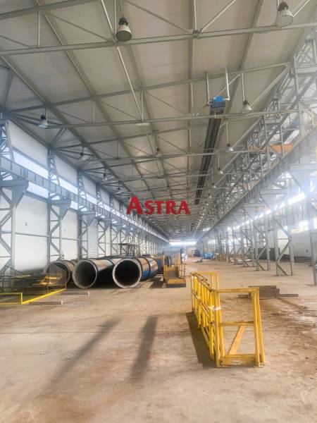 Production facilities with metal structures and piping, Dobšiná. A wide hall with yellow barriers.