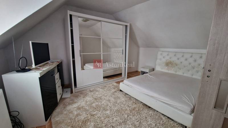 A bright bedroom with a bed, wardrobe, and carpet in a family house.