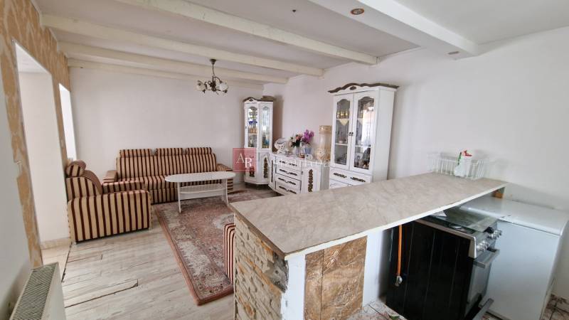 Living room in a family house with striped furniture, a decorative cabinet, and a wooden-patterned floor.
