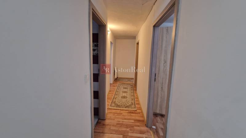 A hallway in a family house with carpet and wood-patterned flooring.