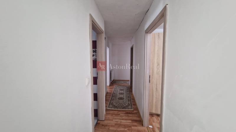 A hallway in a family house with a wooden decor floor and a carpet.
