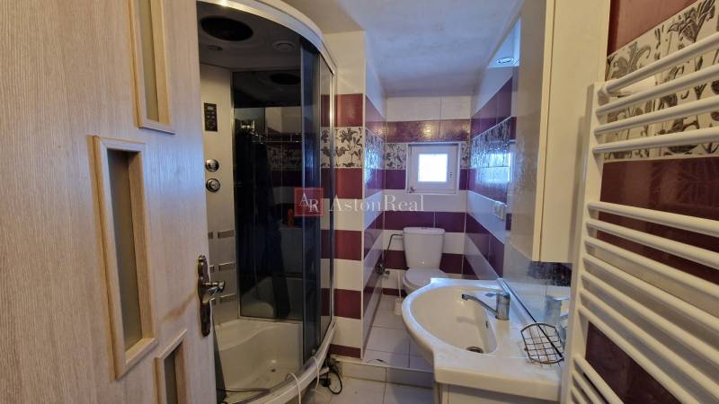 A bathroom in a family house with a shower, sink, and toilet, featuring colorful tiles.