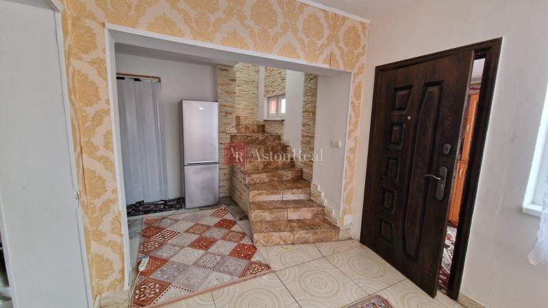 Interior of a family house with a staircase, refrigerator, and decorative wallpaper.