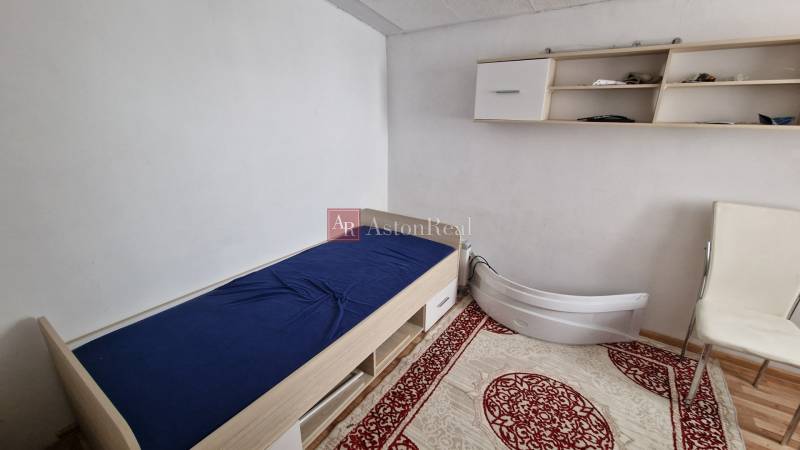 A simple room with a bed and a shelf in a family house.
