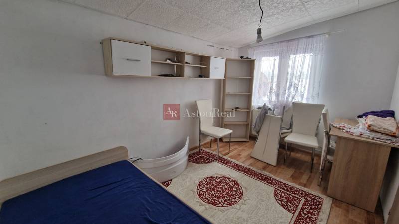 A room in a family house with a bed, shelves, and a floor with a wooden decor.