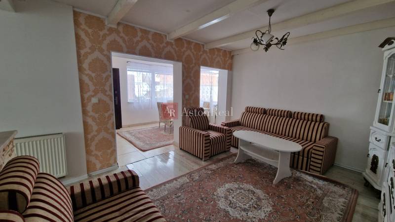 A living room in a family house with patterned wallpaper and striped furniture.