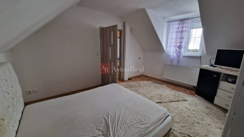 A bedroom in a family house with a wooden decor floor and a light carpeted area.
