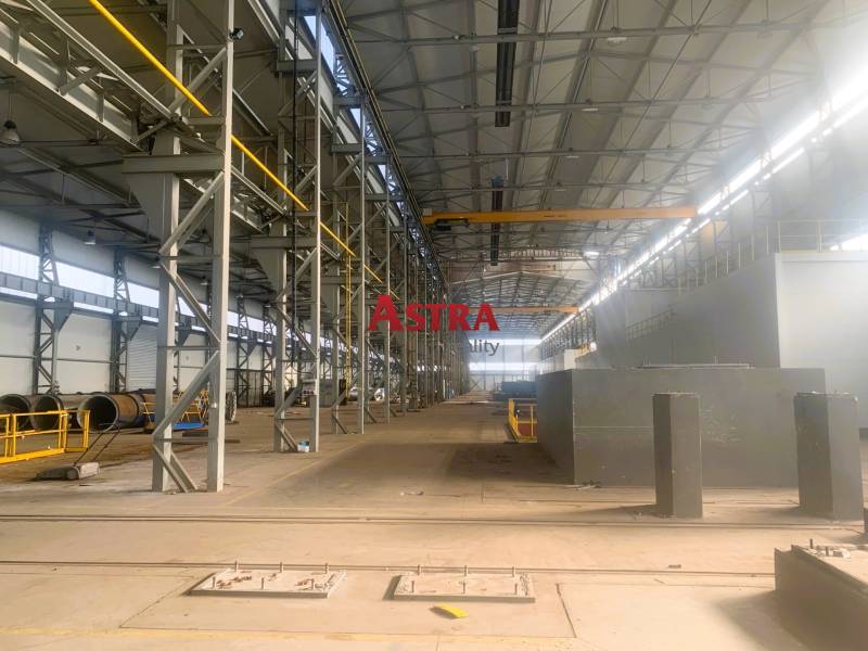 Production facilities with metal structures and a crane inside the hall.